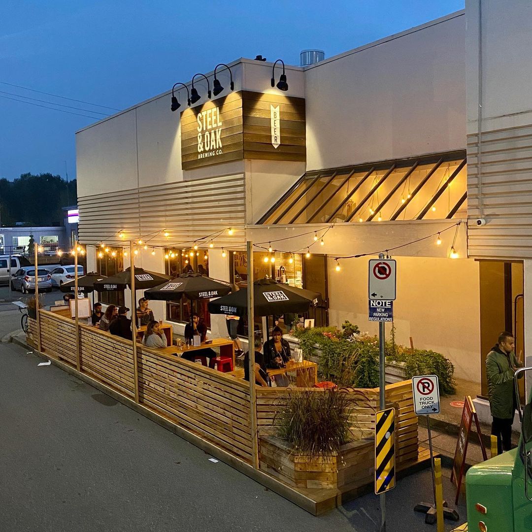 An outdoor brewery patio at evening with lights