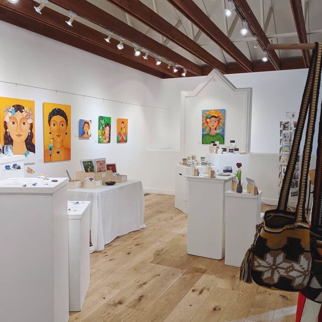 Paintings and other locally made goods on display in a gallery with white walls.