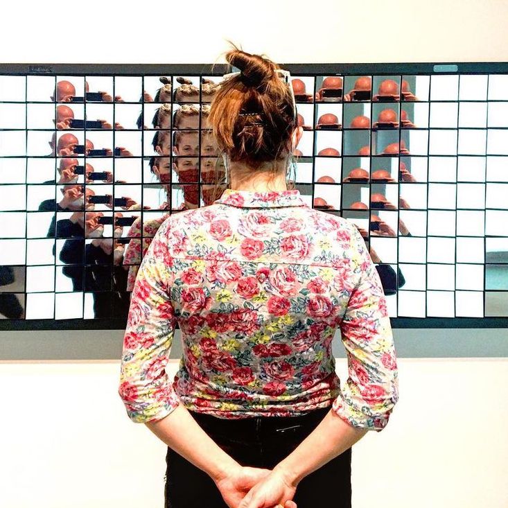 Woman standing in front of mirrored art piece.