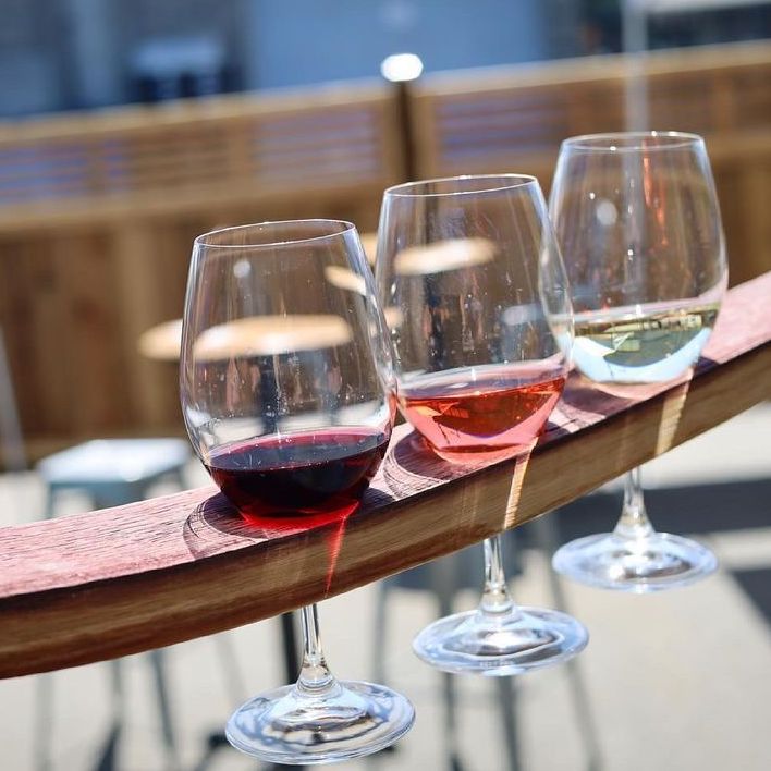 A glass of red wine, rosé, and white wine served as a flight