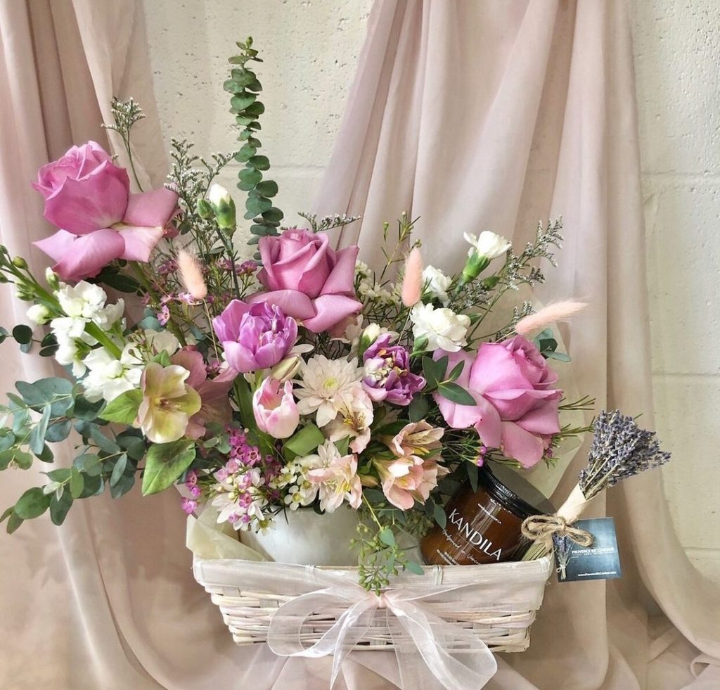 A bouquet of pink roses and flowers in a white basket