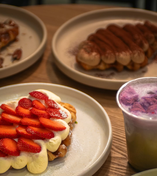 3 Plates, one with strawberries, one with sausages, and a pastry in the other.