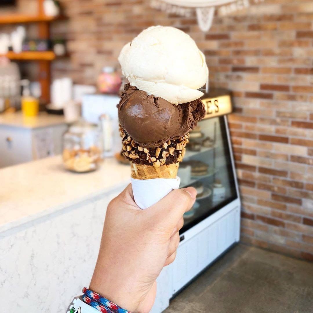 Hand holding ice cream with brick wall and counter in background.